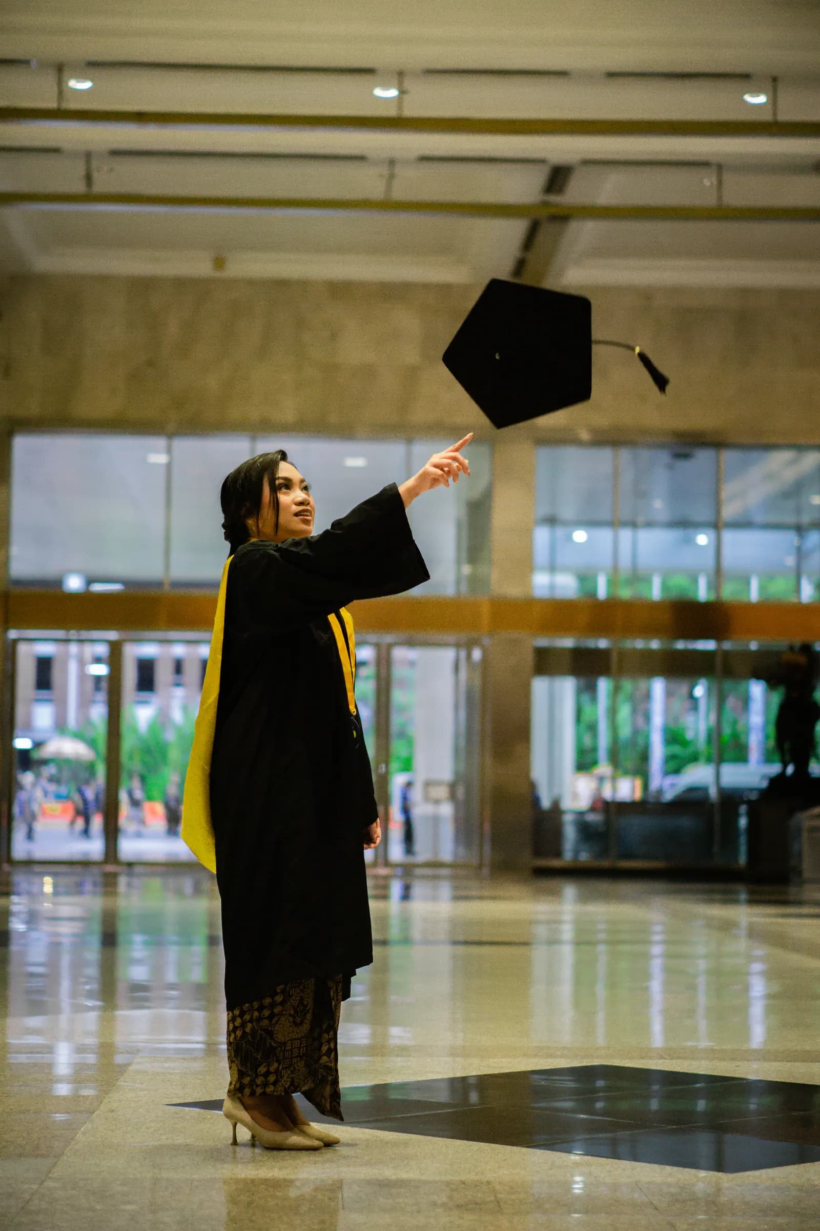 Wisudawati melempar toga di lobi gedung