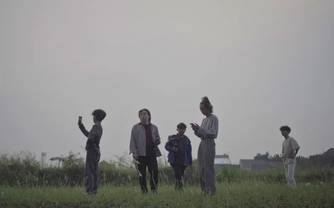 Cuplikan short movie Restart: sekelompok orang berdiri di padang rumput saat senja